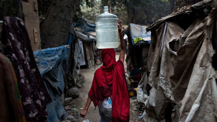 Woman carrying water jug in village alleyway